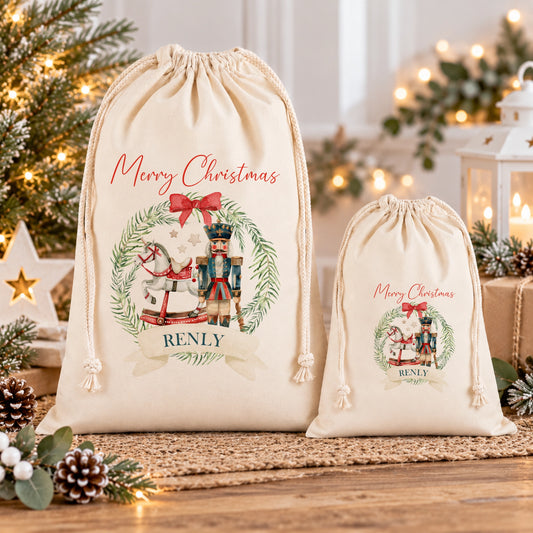 two white drawstring bags with Christmas-themed designs, placed on a wooden surface. The bags are decorated with a nutcracker, a rocking horse, and a wreath, creating a festive and holiday atmosphere.