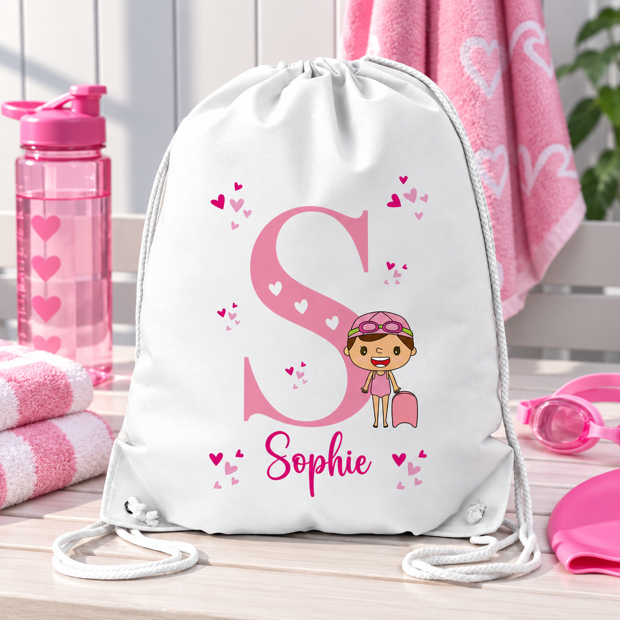 White personalised drawstring swimming bag for girls, featuring a fun pink swimmer design with a large initial and name. Perfect for swimming lessons, leisure swimming, holidays and keeping swimwear and essentials together.