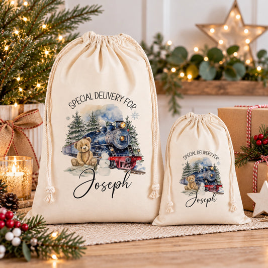 two white drawstring bags with Christmas-themed illustrations and personalized text, placed on a wooden surface.