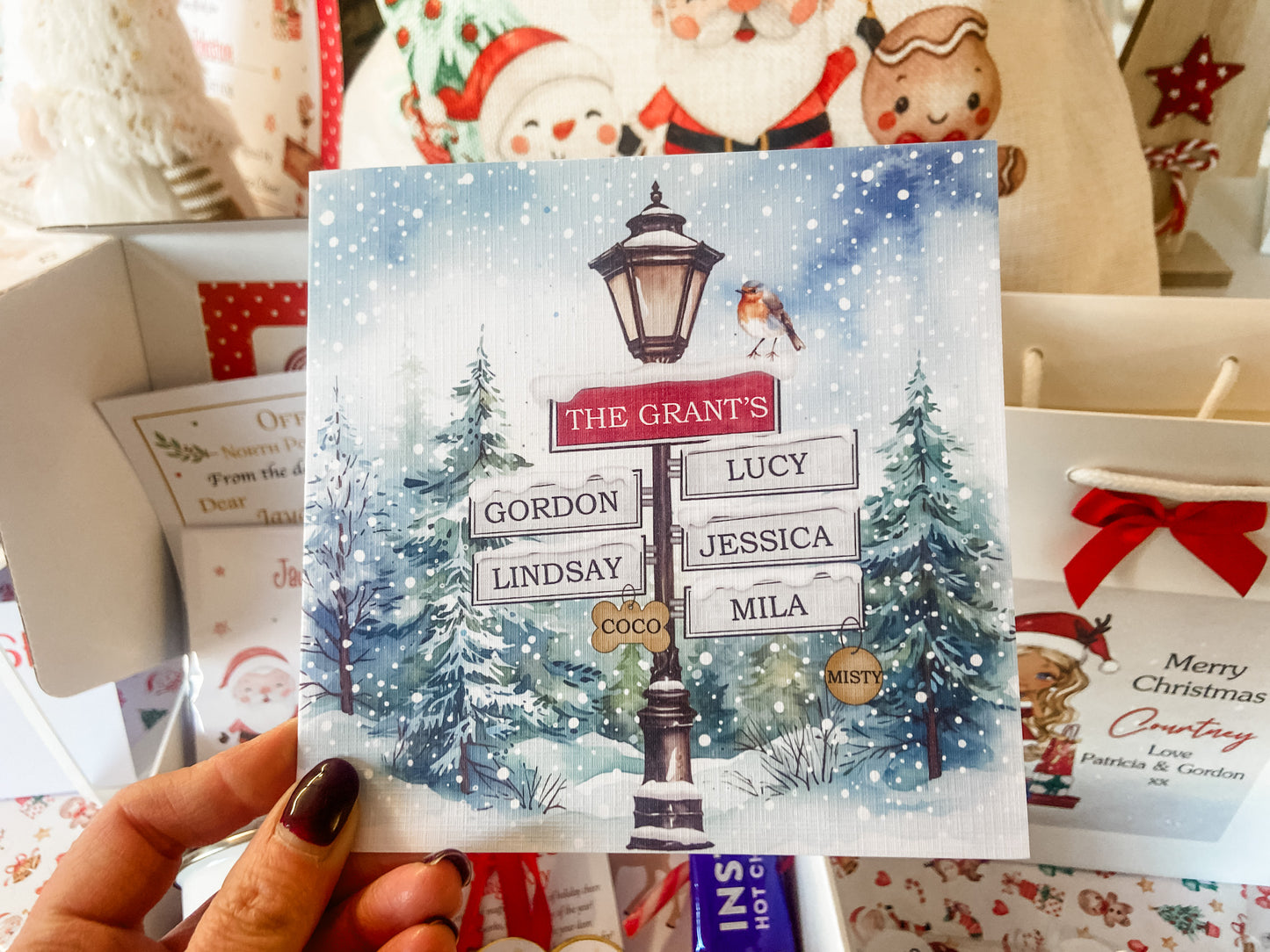 a person holding up a christmas card with a street sign