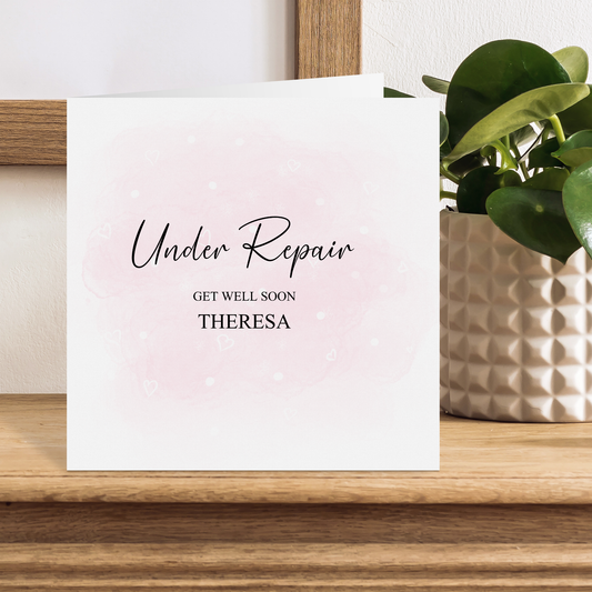 a card with the words under repair on it next to a potted plant