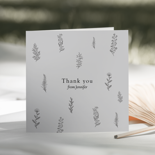 a thank you card sitting on a table next to an open book