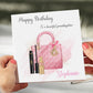 a woman holding a birthday card with a pink purse