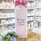 a card with a pink bow on top of a table