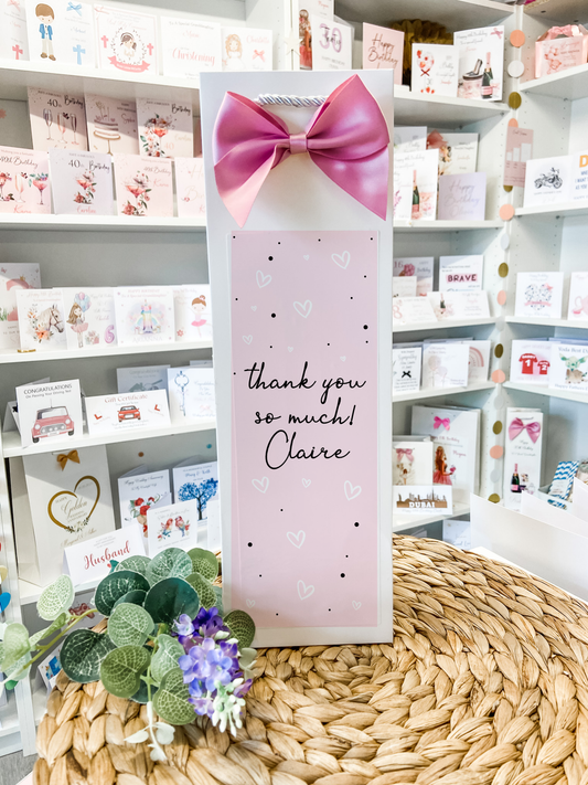 a card with a pink bow on top of a table