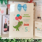a birthday card with a dinosaur holding balloons