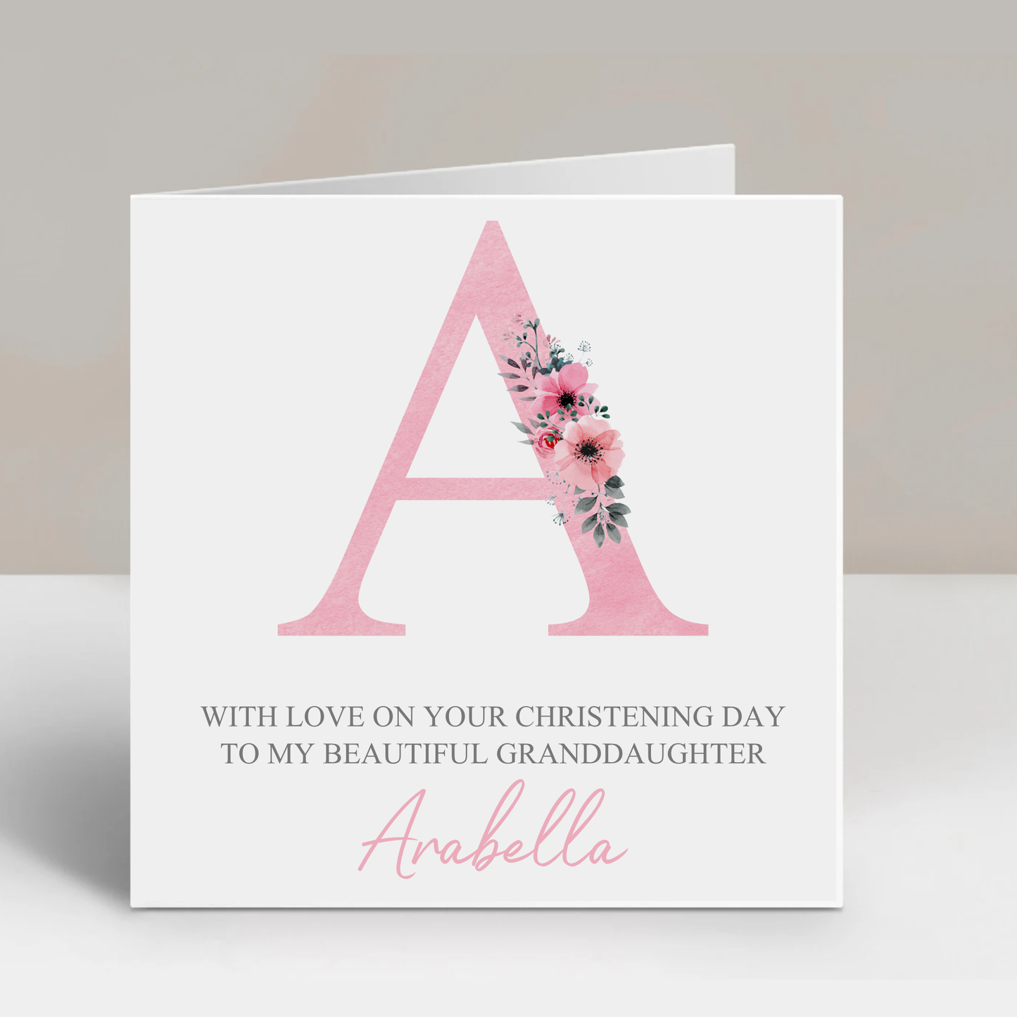 a card with a pink letter and flowers on it