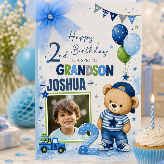 A personalized 2nd birthday grandson card featuring a blue and white theme with a teddy bear, balloons, and a photo placeholder, styled on a decorated birthday table with a cupcake and balloons.