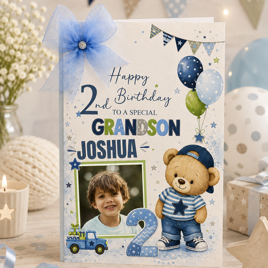 A personalized 2nd birthday grandson card featuring a blue bow, balloons, a teddy bear, and a photo frame, styled on a wooden surface with festive decorations.