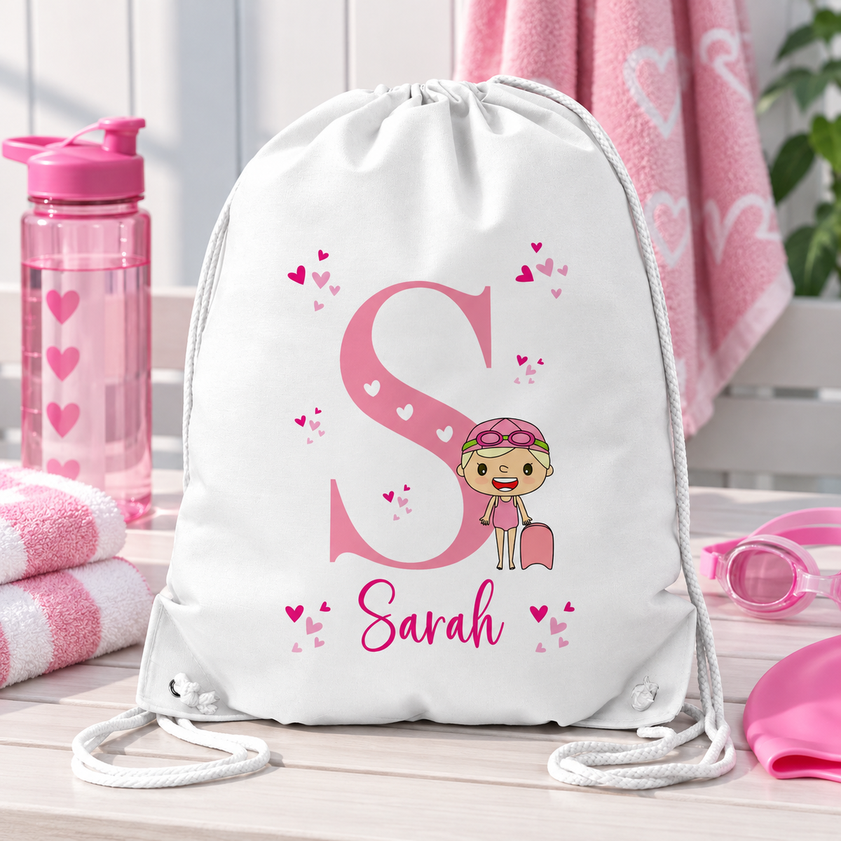 White personalised drawstring swimming bag for kids, featuring a fun pinkswimmer design with a large initial and name. Perfect for swimming lessons, leisure swimming, holidays and keeping swimwear and essentials together.