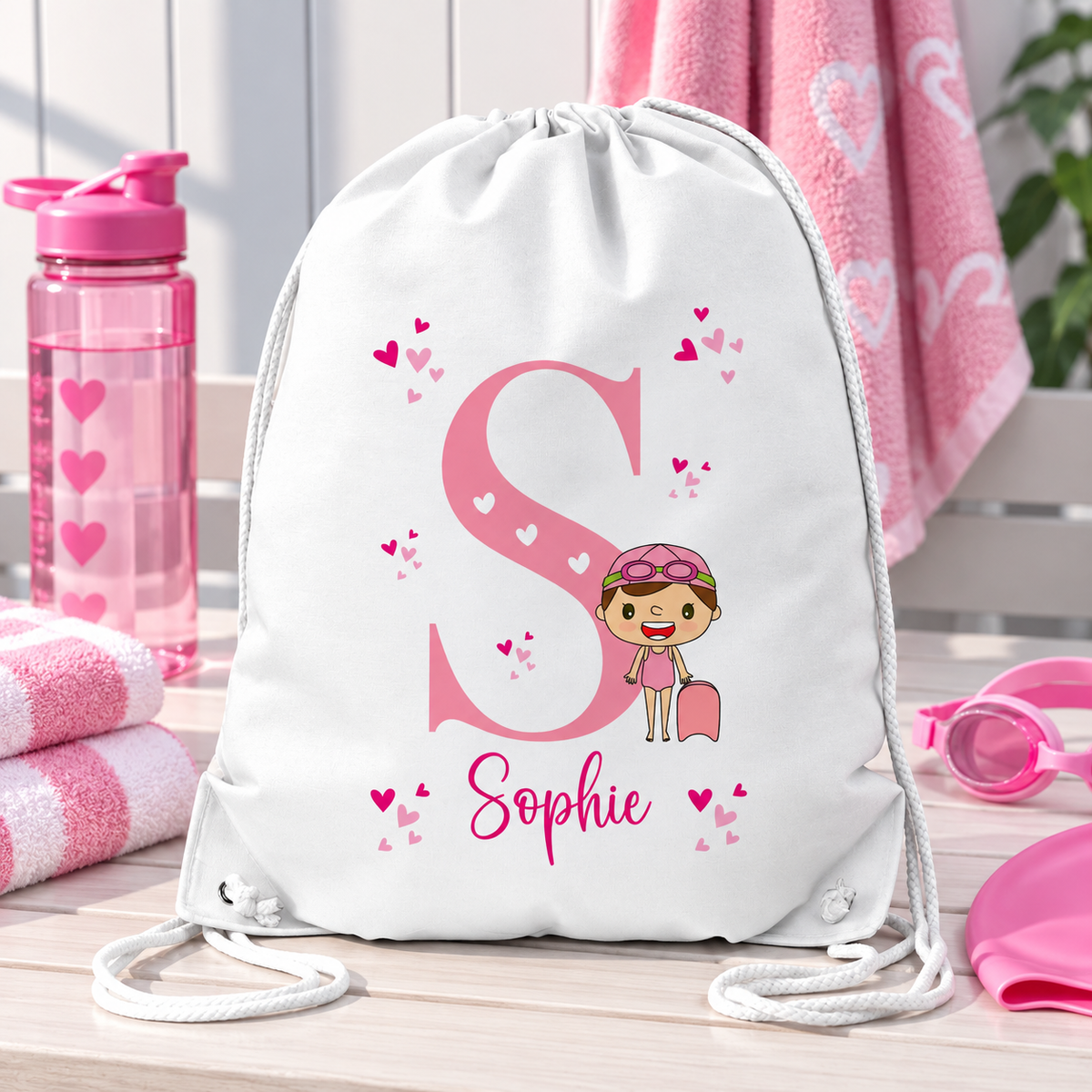 White personalised drawstring swimming bag for girls, featuring a fun pink swimmer design with a large initial and name. Perfect for swimming lessons, leisure swimming, holidays and keeping swimwear and essentials together.