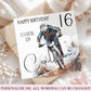 A custom 16th birthday card for a son, featuring a photo of a mountain biker and the name 'Calvin' in script, styled on top of kraft paper envelopes and white fabric with dried flowers.