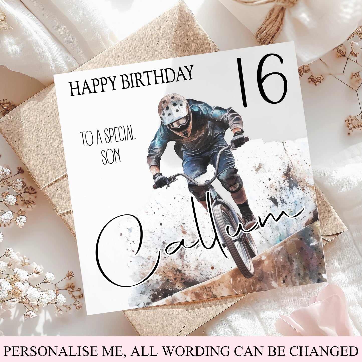 A custom 16th birthday card for a son, featuring a photo of a mountain biker and the name 'Calvin' in script, styled on top of kraft paper envelopes and white fabric with dried flowers.