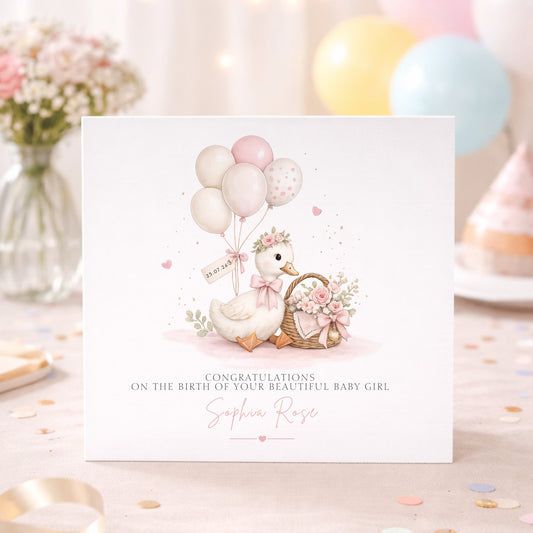 A square baby shower congratulations card featuring a watercolor illustration of a white duckling with pink bow, balloons, and a floral basket. The card reads 'CONGRATULATIONS ON THE BIRTH OF YOUR BEAUTIFUL BABY GIRL' with the name 'Sophia Rose' in pink script.