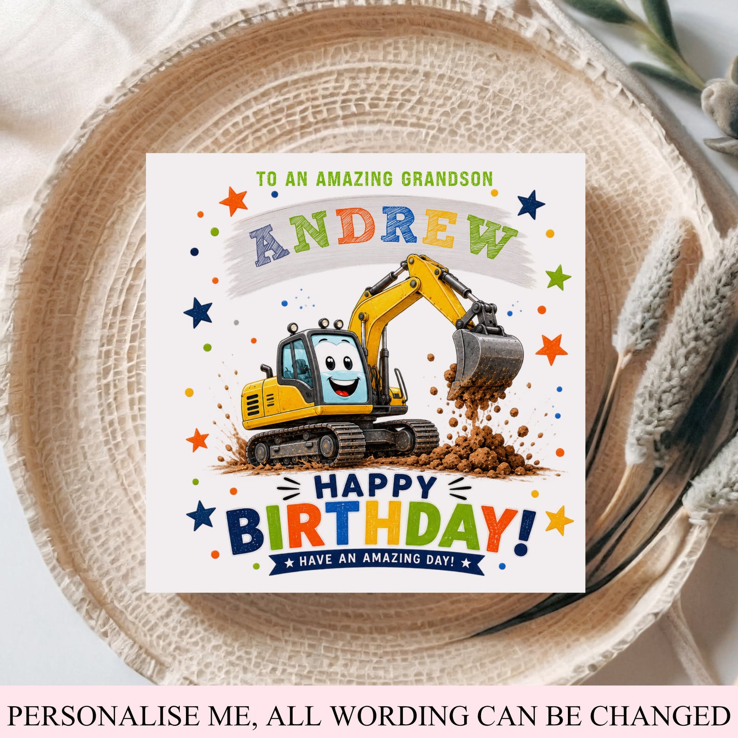 A personalized birthday card for a grandson, featuring a cartoon yellow excavator digging up dirt, with the text 'TO AN AMAZING GRANDSON ANDREW HAPPY BIRTHDAY! HAVE AN AMAZING DAY!'. The card is displayed on a woven straw hat with a pink fabric background.