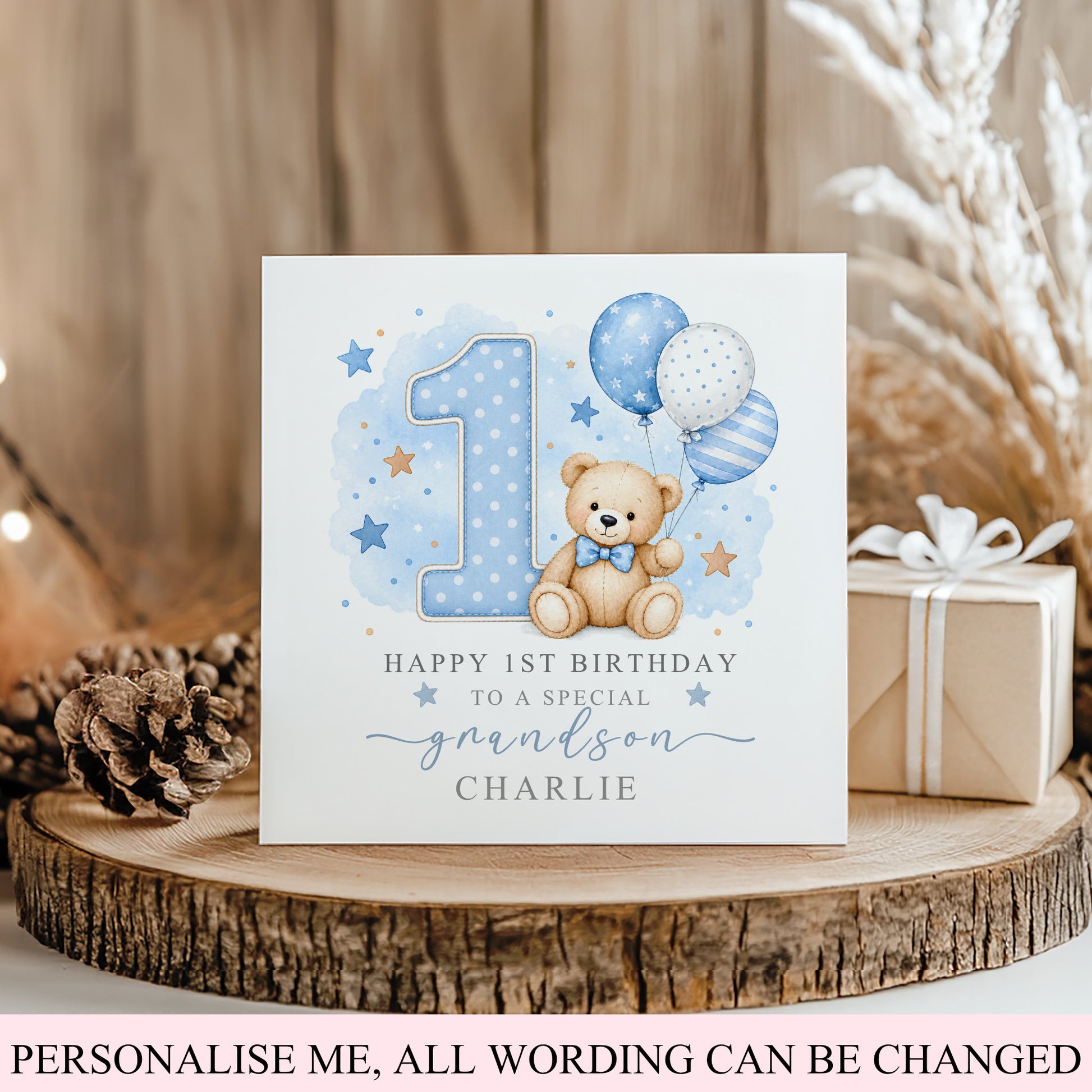 A customisable first birthday card for a grandson, featuring a watercolor teddy bear, balloons, stars, and a large number 1. The card is styled on a rustic wooden slice with a pinecone and a wrapped gift box against a warm wood panel background.