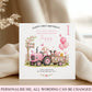 A customisable first birthday card for a granddaughter, featuring a pink tractor with cartoon animals, balloons, and a tree, displayed on a wooden surface with draped cream fabric.