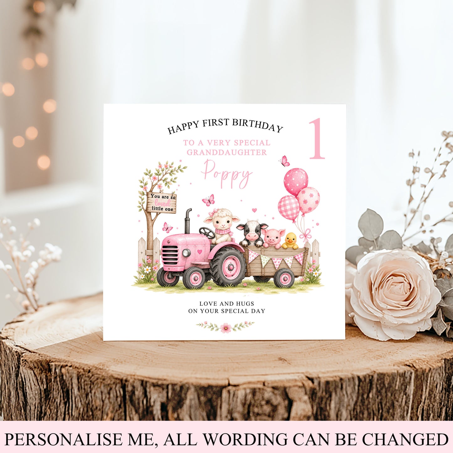 A personalized first birthday card for a granddaughter, featuring a pink tractor and cartoon animals, displayed on a rustic wood slice with a rose and boho decor.