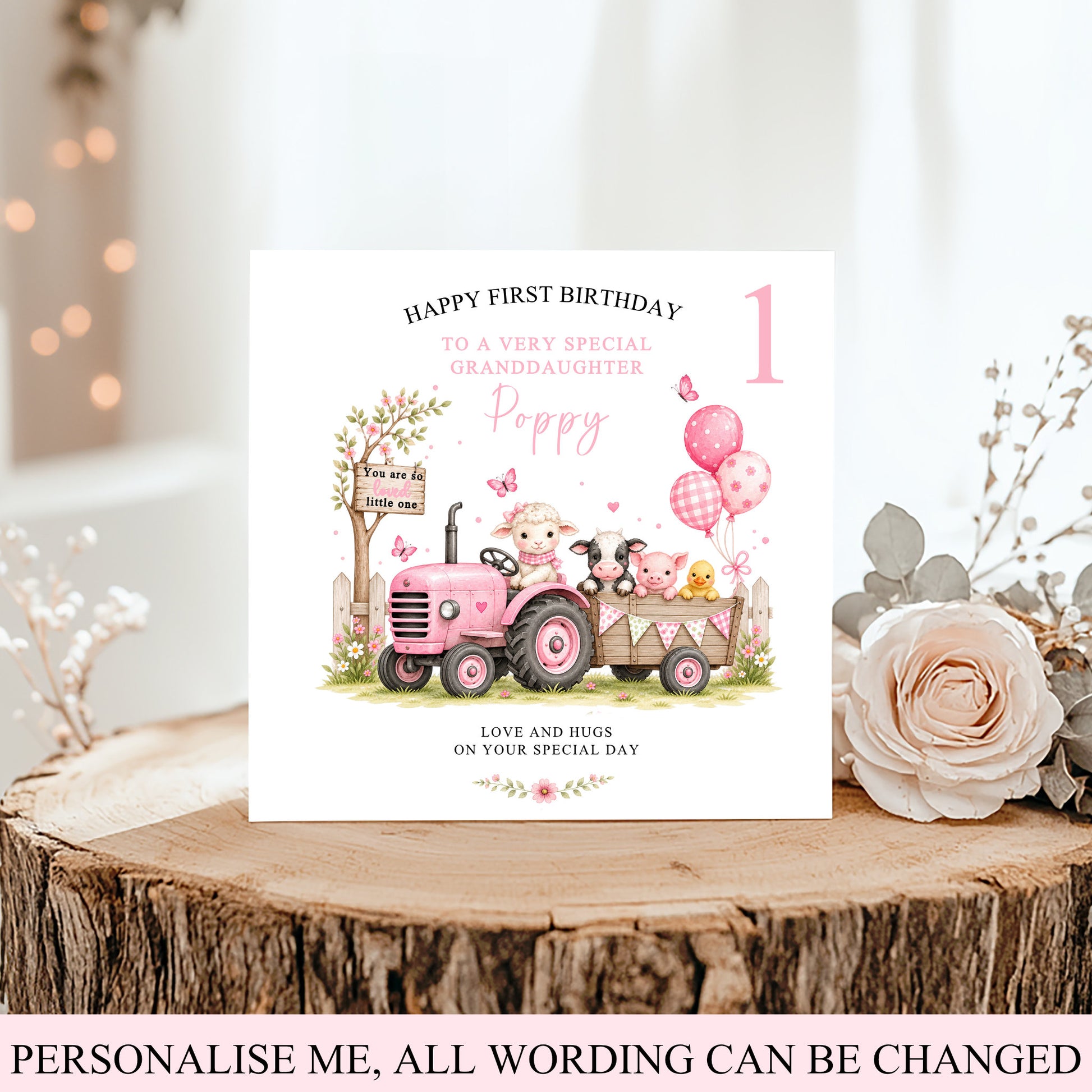 A personalized first birthday card for a granddaughter, featuring a pink tractor and cartoon animals, displayed on a rustic wood slice with a rose and boho decor.