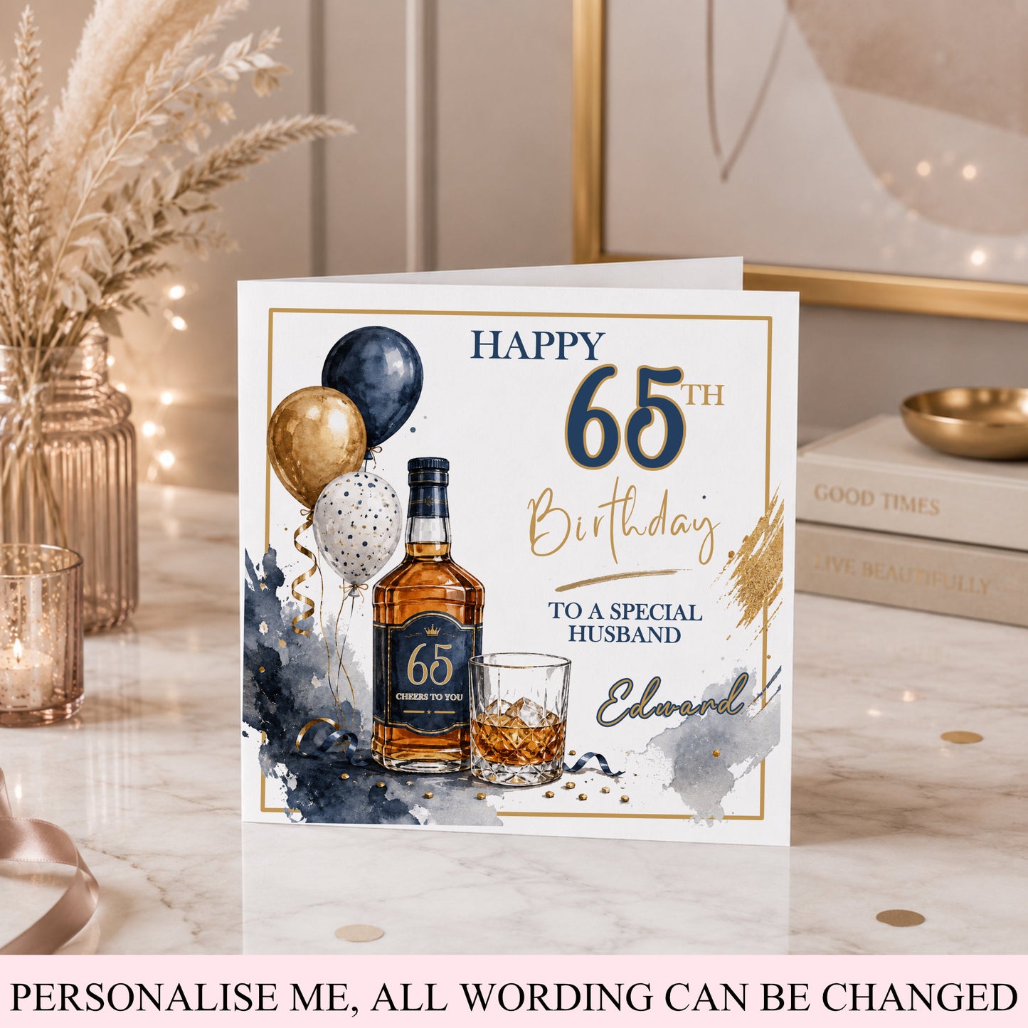 A personalized 65th birthday card for a husband, styled on a marble tabletop with warm boho decor. The card features a watercolor design with a bottle of whiskey, a glass, balloons, and gold and navy blue text that reads 'HAPPY 65TH Birthday TO A SPECIAL HUSBAND'.