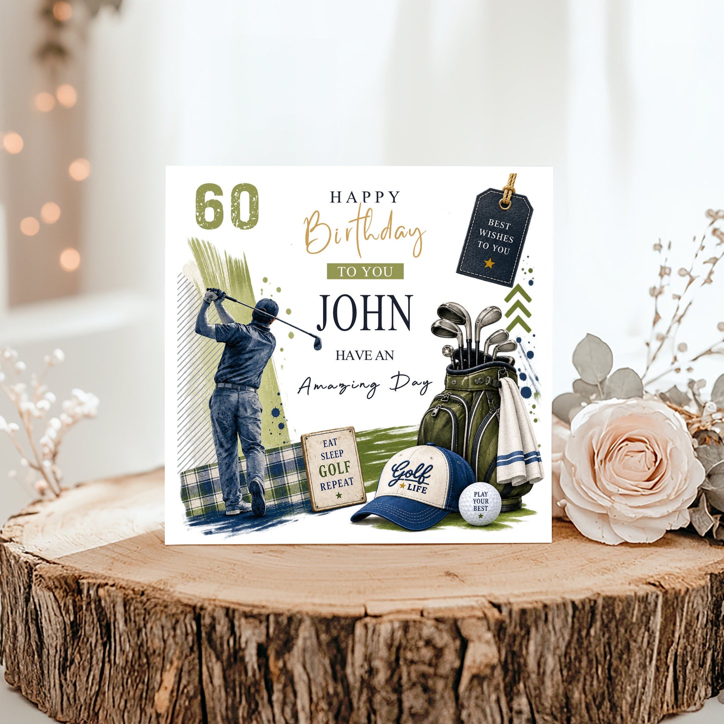 A personalized golf-themed 60th birthday card displayed on a rustic wood slice with decorative flowers. The card features a golf course illustration, a golfer, a golf bag with clubs, a cap, a golf ball, and text reading 'Happy Birthday to you John Have an Amazing Day' along with '60'.
