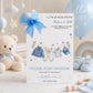 A white new baby boy greeting card displayed upright in a softly styled neutral setting. The card features a blue denim baby jacket, cream trousers, a blue and white striped top and a matching blue baby cap hanging from a decorative clothesline. Blue hearts, gold stars and delicate botanical details surround the clothing.