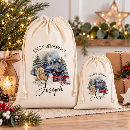 two white drawstring bags with Christmas-themed illustrations and personalized text, placed on a wooden surface.