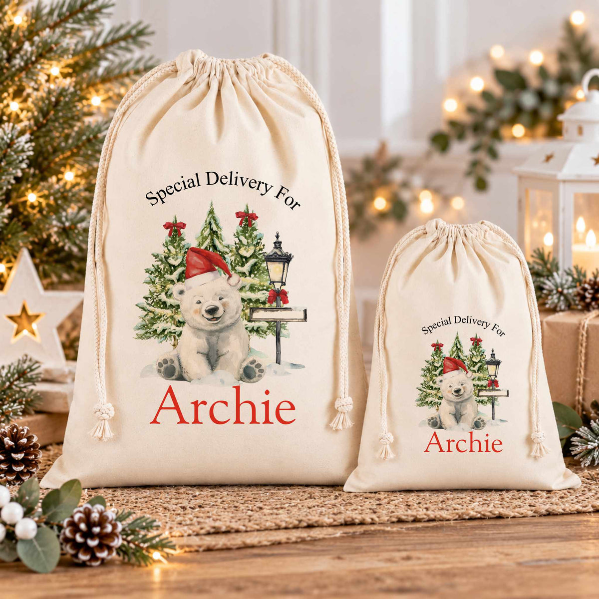 two white drawstring bags with Christmas-themed illustrations and text, placed on a wooden surface.