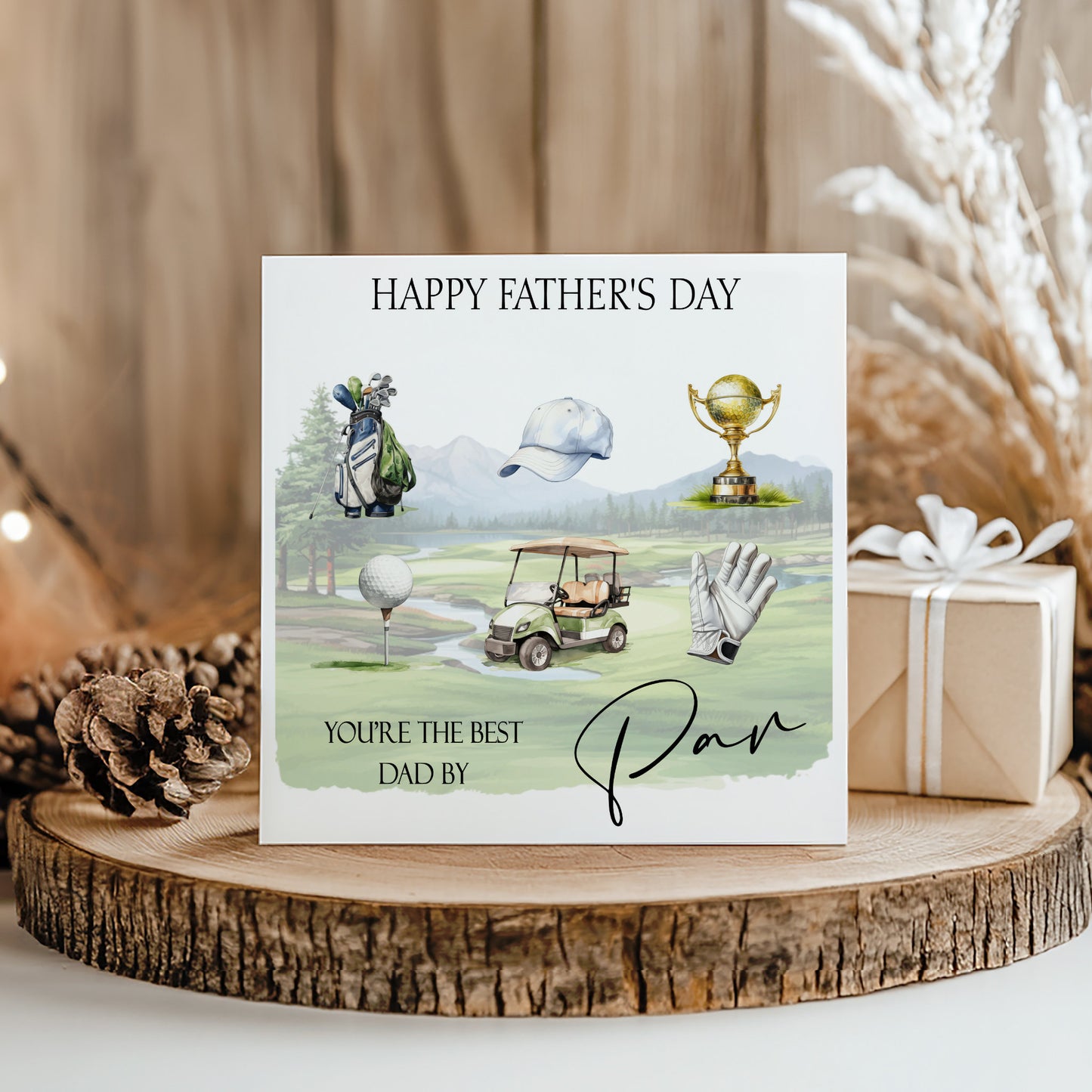 A greeting card with golf-related illustrations and text, placed on a wooden surface with a gift box and pine cone nearby.
