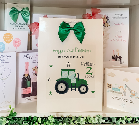 a birthday card with a tractor and a green bow