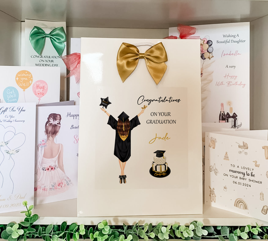 a card with a picture of a girl wearing a graduation outfit and a gold bow
