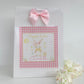a white paper bag with a pink bow on top of it