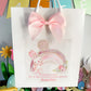a white bag with a pink bow on top of it