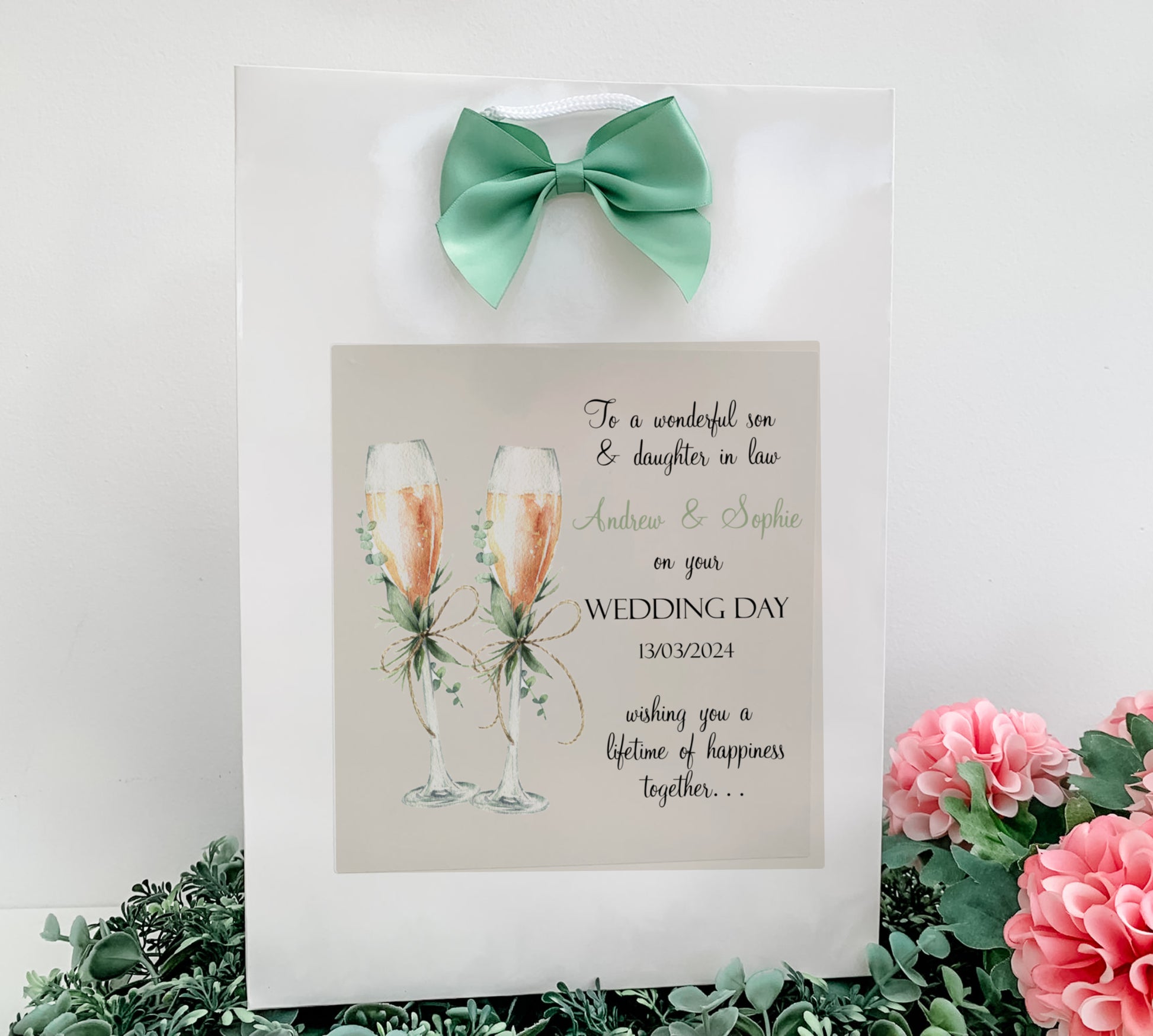 a picture of two champagne flutes with a green bow